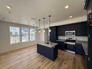 Kitchen with light wood-style flooring, a textured ceiling, visible vents, a sink, and stainless steel appliances