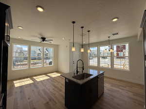 Kitchen with a textured ceiling, dishwasher, a sink, and baseboards