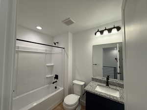 Bathroom featuring visible vents, baseboards, toilet, vanity, and shower / tub combination