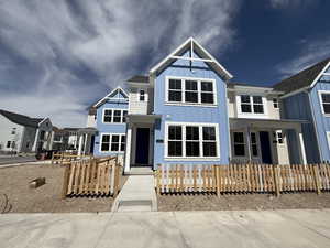 View of front facade with covered porch, board and batten siding, and a fenced front yard