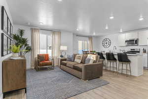 Living area featuring a textured ceiling, recessed lighting, and light wood-type flooring