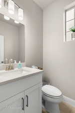 Bathroom featuring toilet, vanity, and baseboards