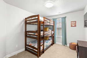 Carpeted bedroom featuring baseboards, visible vents, and a textured ceiling