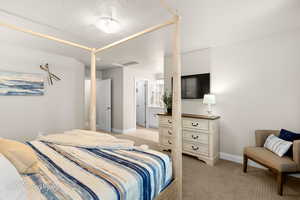 Bedroom with connected bathroom, baseboards, and light carpet