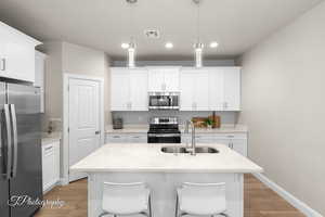 Kitchen with visible vents, light wood-style flooring, stainless steel appliances, and a sink