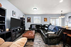 Living area featuring baseboards, wood finished floors, and a notable chandelier