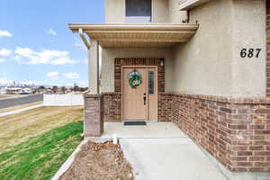 View of exterior entry with stucco siding and a yard