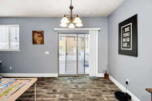 Entryway with an inviting chandelier, dark wood-style floors, baseboards, and visible vents