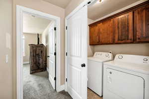 Laundry room featuring light colored carpet, separate washer and dryer, cabinet space, and a textured ceiling