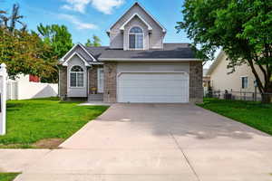 View of front facade with brick siding, driveway, an attached garage, and a shingled roof