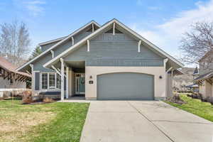 View of front facade featuring board and batten siding, driveway, a front lawn, and an attached garage