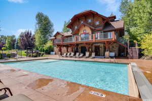 Rear view of property with stone siding, fence, stairs, and a patio