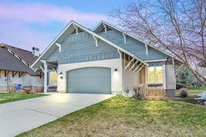 View of front of house featuring a front yard, board and batten siding, concrete driveway, and a garage
