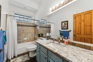 Full bathroom with toilet, vanity, and shower / tub combo with curtain