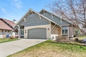 View of front facade with board and batten siding, concrete driveway, a garage, and a front lawn