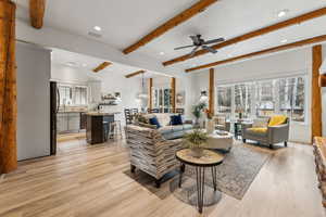Living room featuring visible vents, beam ceiling, light wood-style floors, and ceiling fan