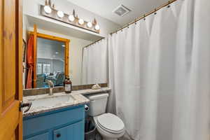 Full bathroom with toilet, vanity, connected bathroom, and visible vents