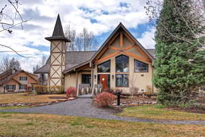 View of front facade with a front lawn, stucco siding, and roof with shingles