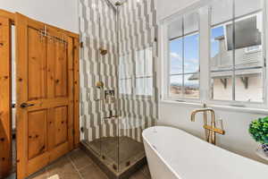 Bathroom with a freestanding bath, tile patterned flooring, and a shower stall