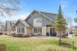 Rear view of house featuring stucco siding, a shingled roof, a patio area, and a lawn