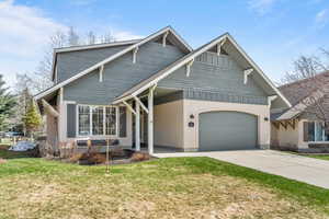 View of front of home with a front yard, concrete driveway, stucco siding, and an attached garage