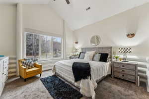 Carpeted bedroom with visible vents, high vaulted ceiling, and ceiling fan