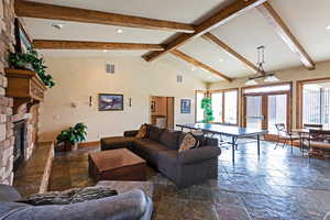 Living area with visible vents, plenty of natural light, beamed ceiling, and stone tile floors