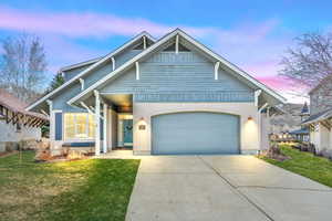 View of front of house featuring driveway, an attached garage, and a lawn