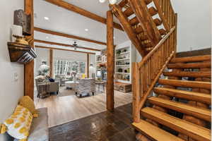 Staircase featuring beamed ceiling, stone tile floors, recessed lighting, and a ceiling fan