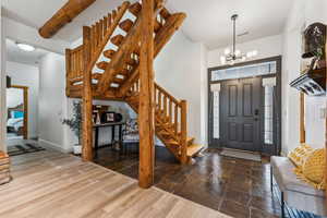 Entryway featuring visible vents, a chandelier, baseboards, stairs, and wood finished floors