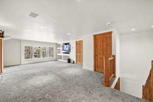 Unfurnished living room featuring carpet, baseboards, and recessed lighting