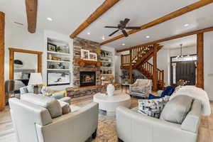 Living area featuring stairs, built in shelves, light wood-style flooring, beamed ceiling, and ceiling fan