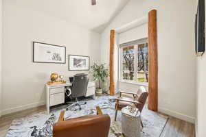 Office space with baseboards, lofted ceiling, and light wood-style floors
