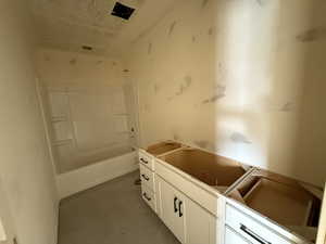Bathroom with tub / shower combination, vanity, and a textured ceiling