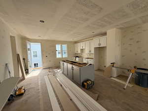 Kitchen featuring white cabinetry, wallpapered walls, a kitchen island, and washing machine and dryer
