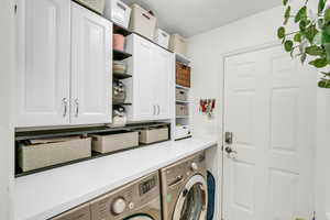 Washroom featuring cabinet space and independent washer and dryer