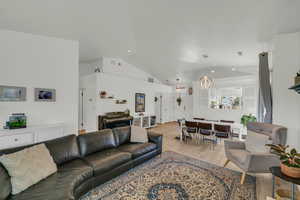 Living area with light wood finished floors, lofted ceiling, and visible vents