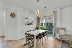 Dining space featuring visible vents, light wood finished floors, baseboards, recessed lighting, and an inviting chandelier