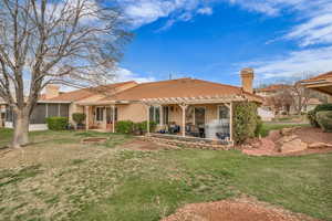 Rear view of property featuring a patio, a chimney, a sunroom, and a yard