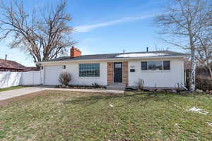 Single story home with driveway, an attached garage, fence, and a front yard