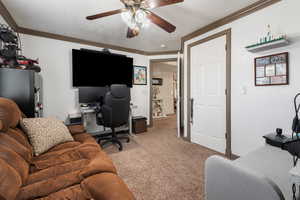Home office featuring ceiling fan, ornamental molding, and light carpet