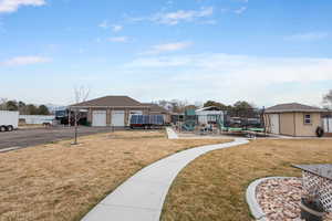 View of yard featuring aphalt driveway, fence, a playground, a garage, and an outdoor structure