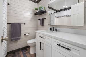 Full bath featuring a shower with curtain, toilet, wood finished floors, and vanity