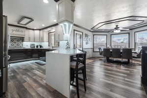 Kitchen featuring a peninsula, dark wood-style flooring, a ceiling fan, and tasteful backsplash