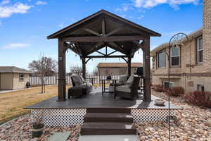 Wooden deck featuring an outdoor structure, fence, a gazebo, outdoor lounge area, and a lawn