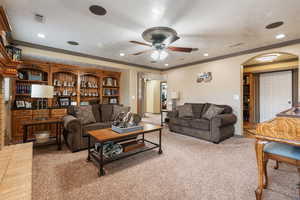 Carpeted living area featuring visible vents, arched walkways, recessed lighting, and a ceiling fan