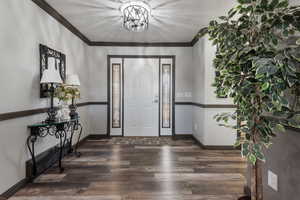 Entryway with baseboards, ornamental molding, and wood finished floors