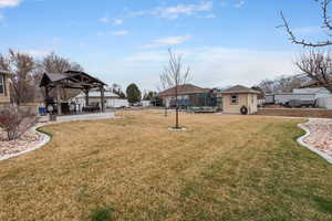 View of yard with fence, a gazebo, a storage unit, an outbuilding, and a patio area