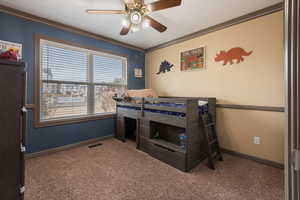 Bedroom with crown molding, carpet flooring, freestanding refrigerator, baseboards, and visible vents