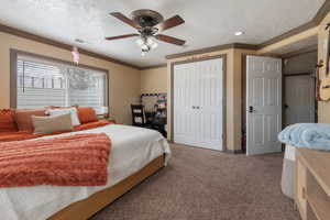 Bedroom with visible vents, crown molding, carpet, and a textured ceiling
